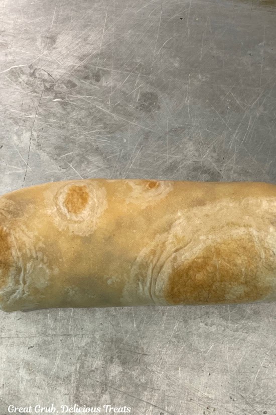 A rolled up chicken burrito that is ready to be fried.