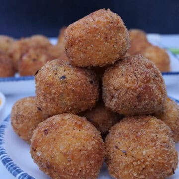 A white plate with blue trim with a stack of 10 bite-size corn casserole bites on it.