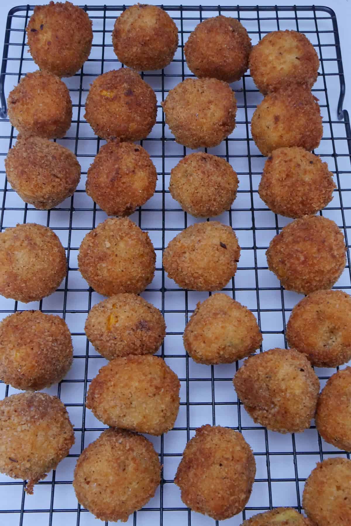 A wire rack with fried corn casserole bites on it.