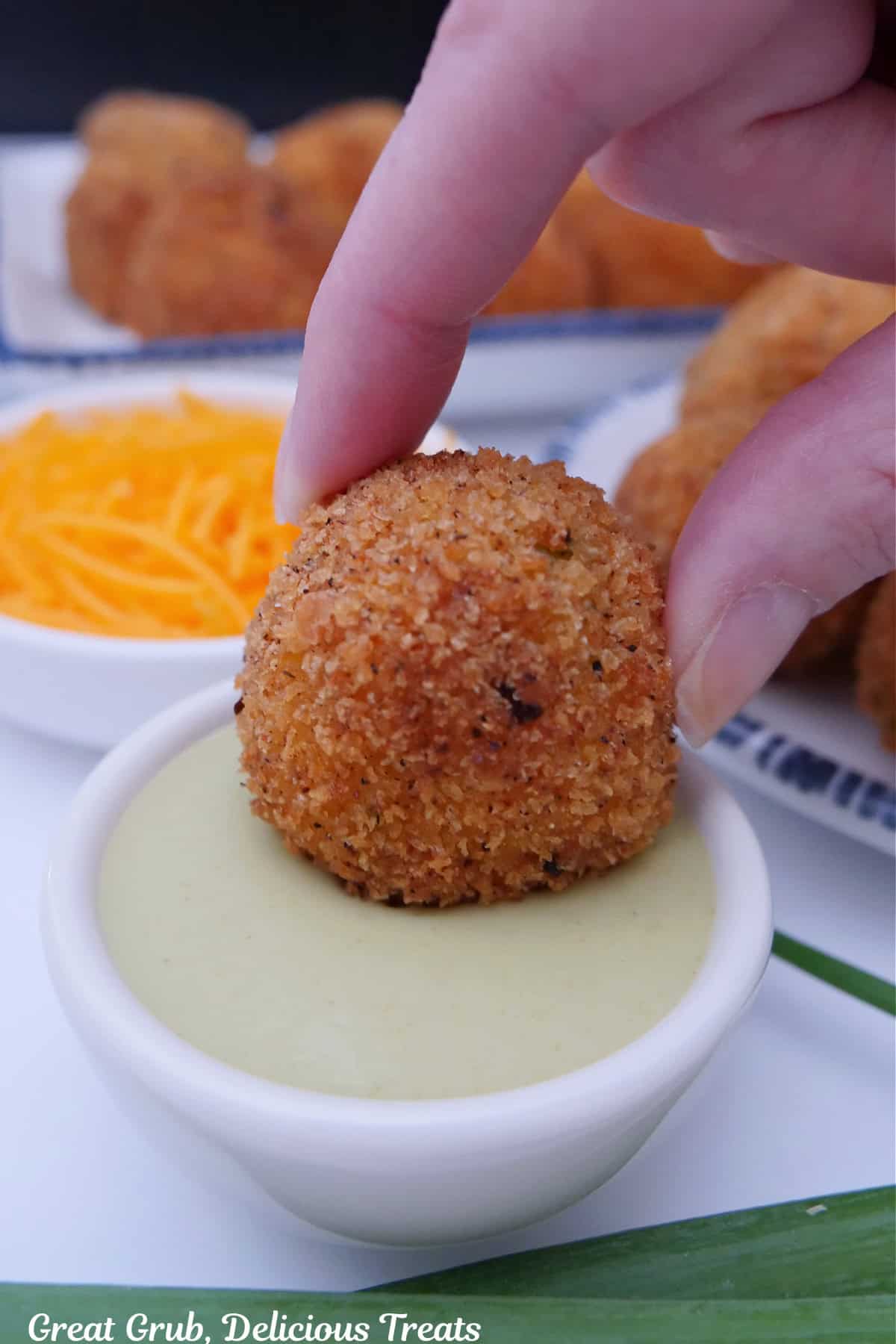 A small white bowl with a corn casserole bite being dipped into sance.