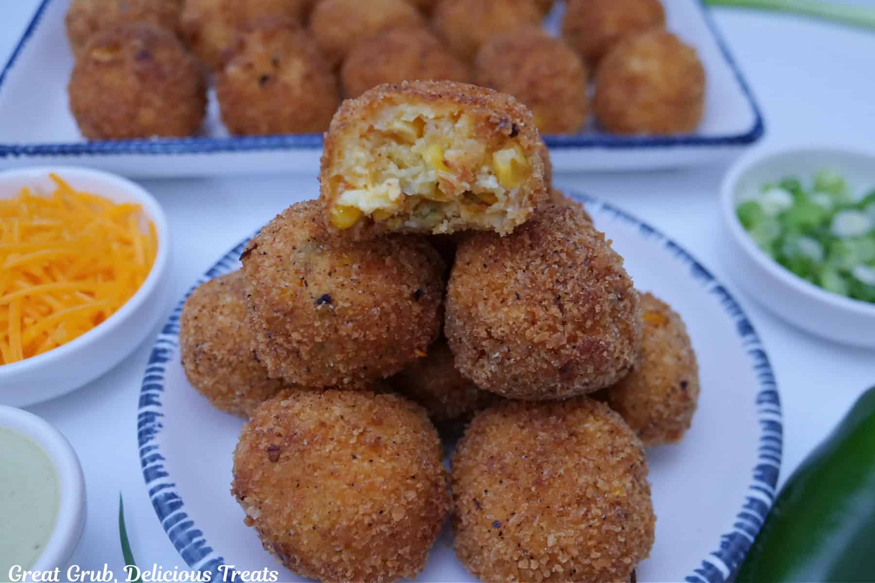 A round white plate with blue trim with fried corn casserole bites on it.