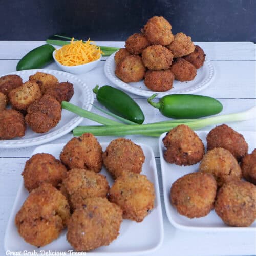 A white surface with four plates filled with fried mac and cheese bites.