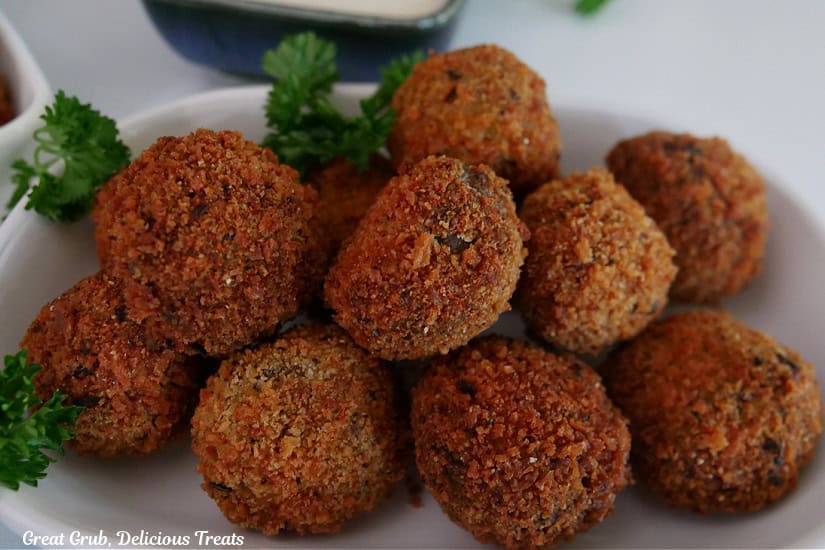 A white oval shallow bowl filled with ten deep fried meatloaf bites.