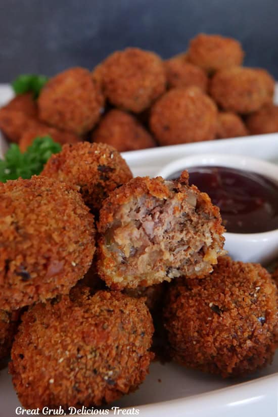 Two white plates with fried meatloaf bites on them with a bite taken out of one.