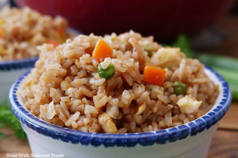 A white bowl with blue trim with a serving of freid rice in it.