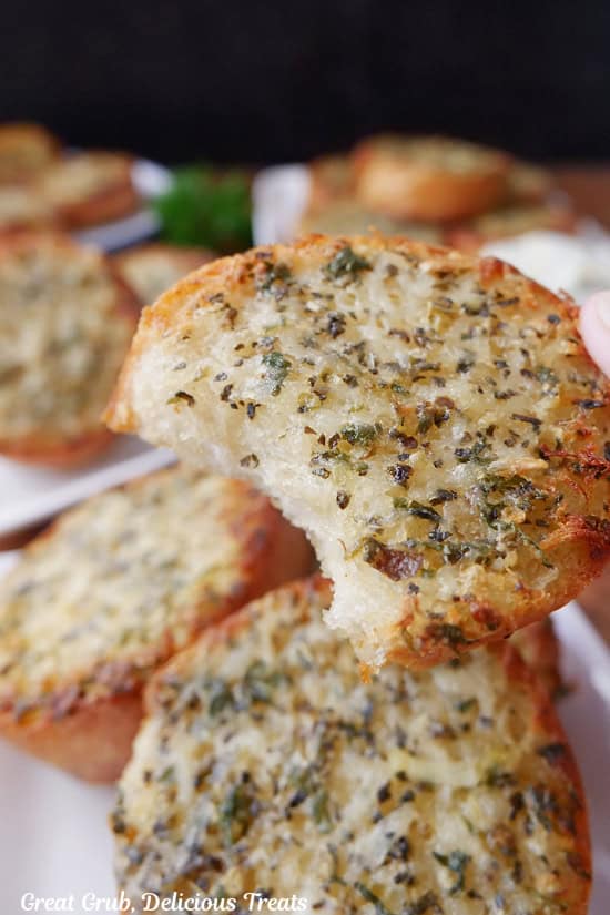 A piece of garlic bread with a bite taken out of it.