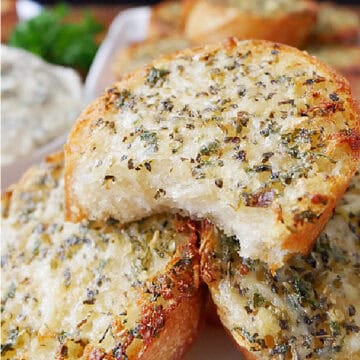A white plate with three small round pieces of garlic bread on it.
