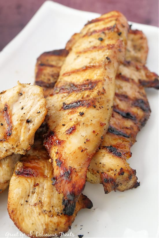 Grilled Chicken Salad is a delicious salad recipe that is perfect for lunch or dinner. Freshly barbecued and sliced chicken breasts on a white plate.