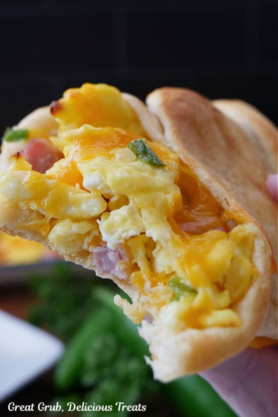 A breakfast crescent filled with eggs, ham, and cheese, with a bite taken out of it.