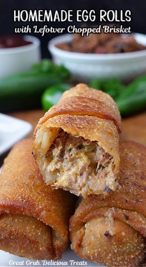 A close up of three egg rolls on a white plate with a bite taken out of one of them.