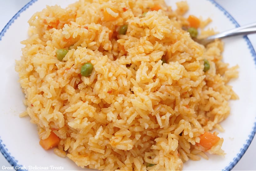 A horizontal photo of a white bowl filled with a serving of homemade Spanish rice.