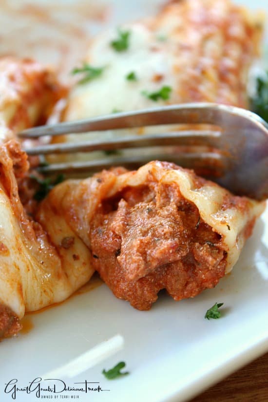 Lasagna Stuffed Manicotti A white plate with stuffed manicotti on it and a fork cutting a bite off.