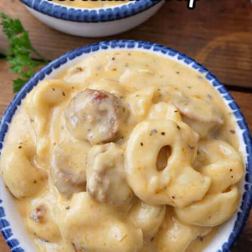 Two white bowls with blue trim filled with a serving of Italian sausage tortellini soup.