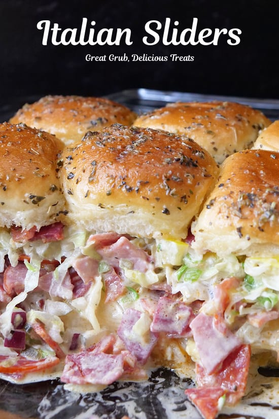 A baking dish with six Italian sliders in it.
