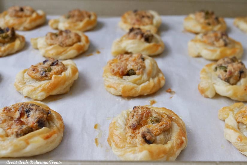 A baking sheet with parchment paper on it and mini jalapeno popper pastry bites on it after being removed from the oven.