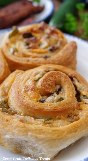 A close up of two crescents pinwheels with the flavors of jalapeno poppers baked in.