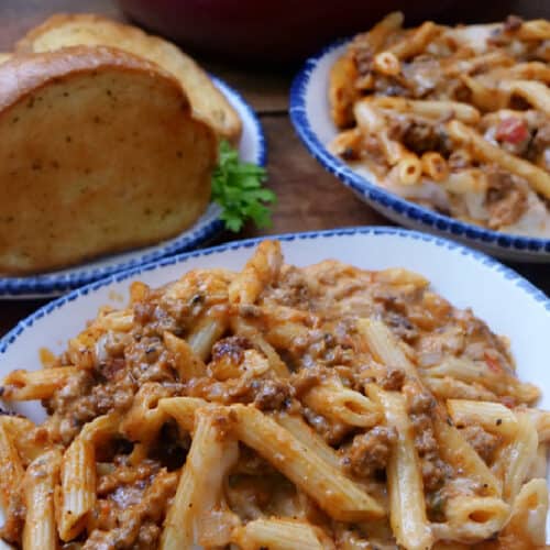 A white bowl with blue trim filled with a serving of pasta.