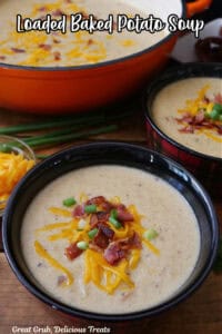 Two red and black plaid bowls filled with a serving of potato soup with a orange pot in the background.