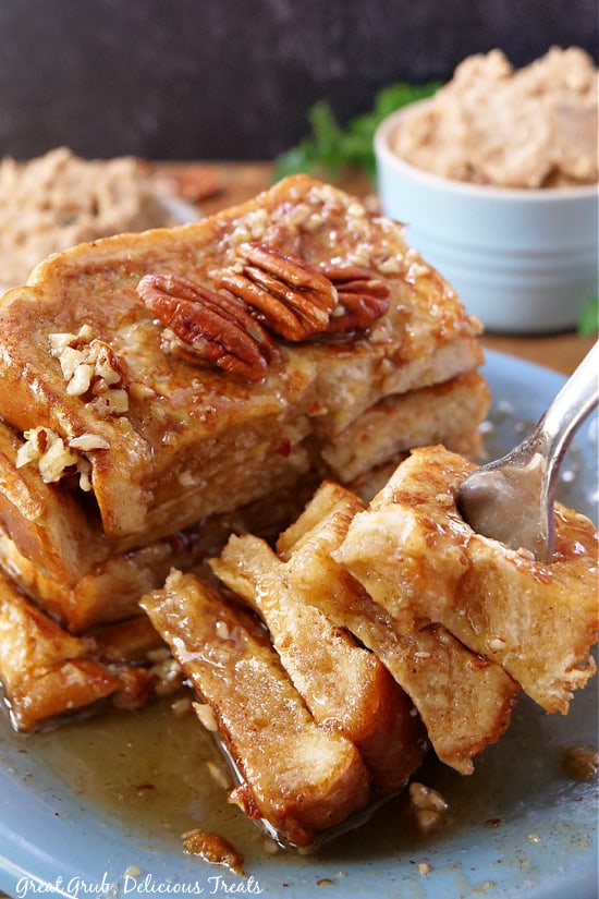 Maple Pecan French Toast is a great breakfast to whip up on Saturday mornings. A stack of French toast, with a big bite on a fork.