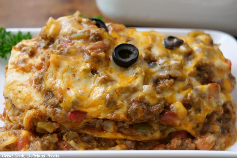 A white oblong plate with a serving of Mexican lasagna on it.