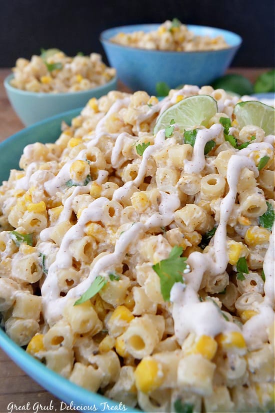 Mexican Street Corn Pasta Salad is a great side dish that is perfect to serve with tacos, enchiladas, or burritos. A close up photo of pasta salad showing all the ingredients, and two small bowls of pasta salad in the background.