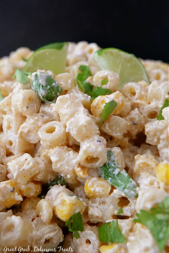Mexican Street Corn Pasta Salad is a quick and easy pasta salad recipe that will surely be a hit. A close up photo showing noodles, corn, and cilantro all covered in street corn dressing.