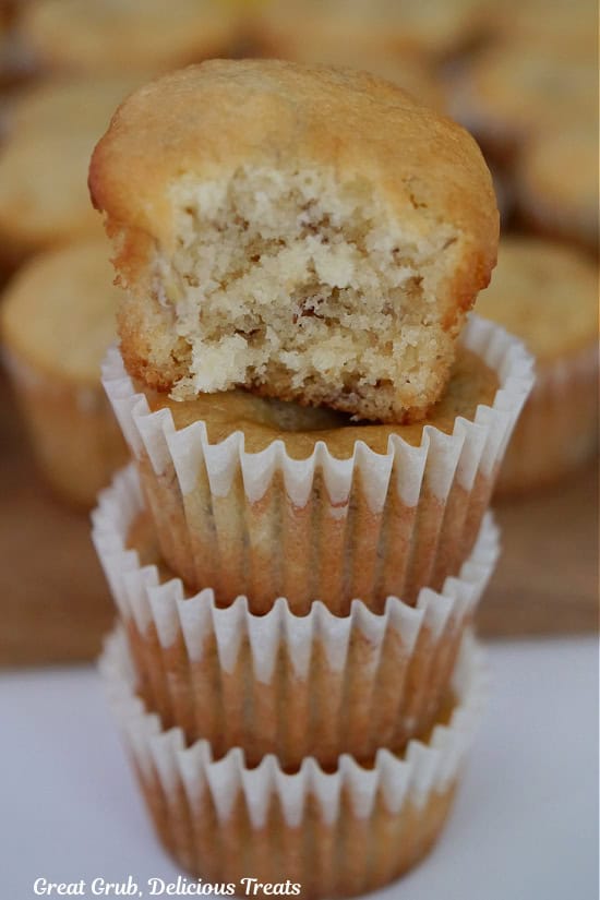 A stack of mini muffins on top of each other with a bite out of the muffin on top.