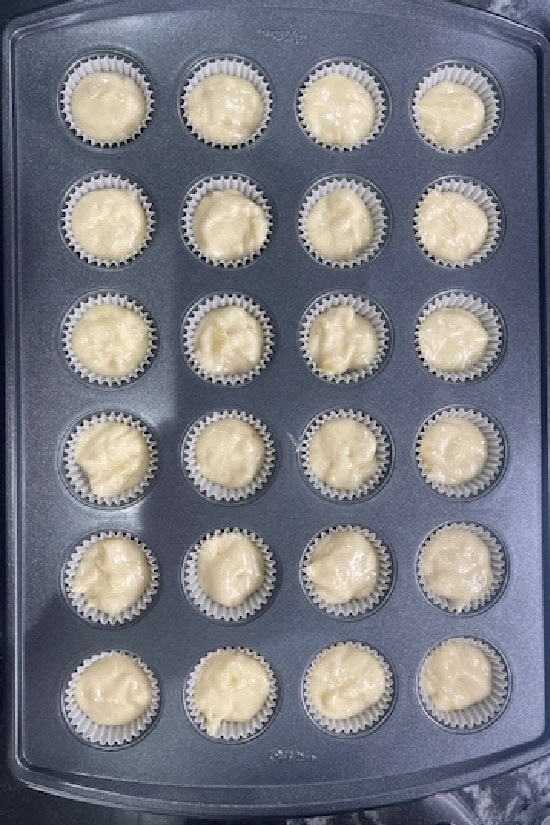 A mini muffin pan with the banana muffin batter in it before being baked.