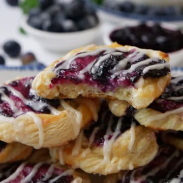 A small stack of mini blueberry pastries with a bite taken out of the pastry on top.
