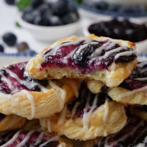 A small stack of mini blueberry pastries with a bite taken out of the pastry on top.