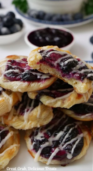 Bite-size blueberry pastries on a white surface with a bite taken out of the pastry on top of the small stack.