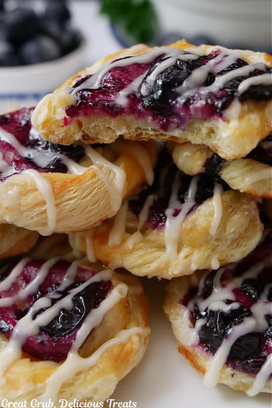 A close up of a few bite-size blueberry pastries with a bite taken out of the one on top.