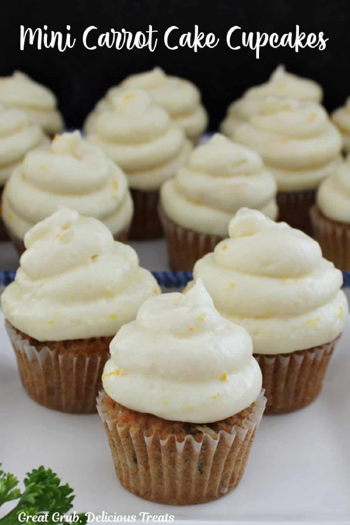 A white surface with mini cupcakes with frosting on it.