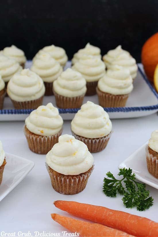 A white surface with mini cupcakes with frosting on it.