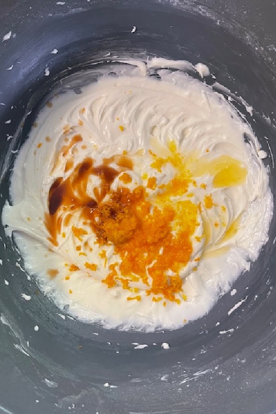 A bowl with the orange buttercream frosting ingredients in it.