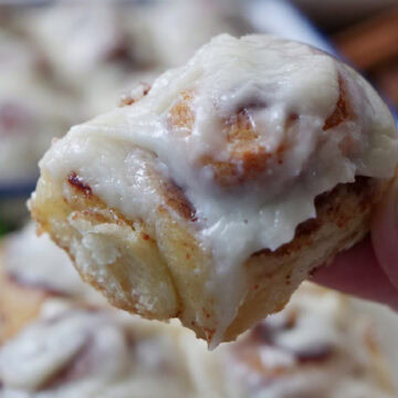 A single mini cinnamon rolls held above the serving plate.