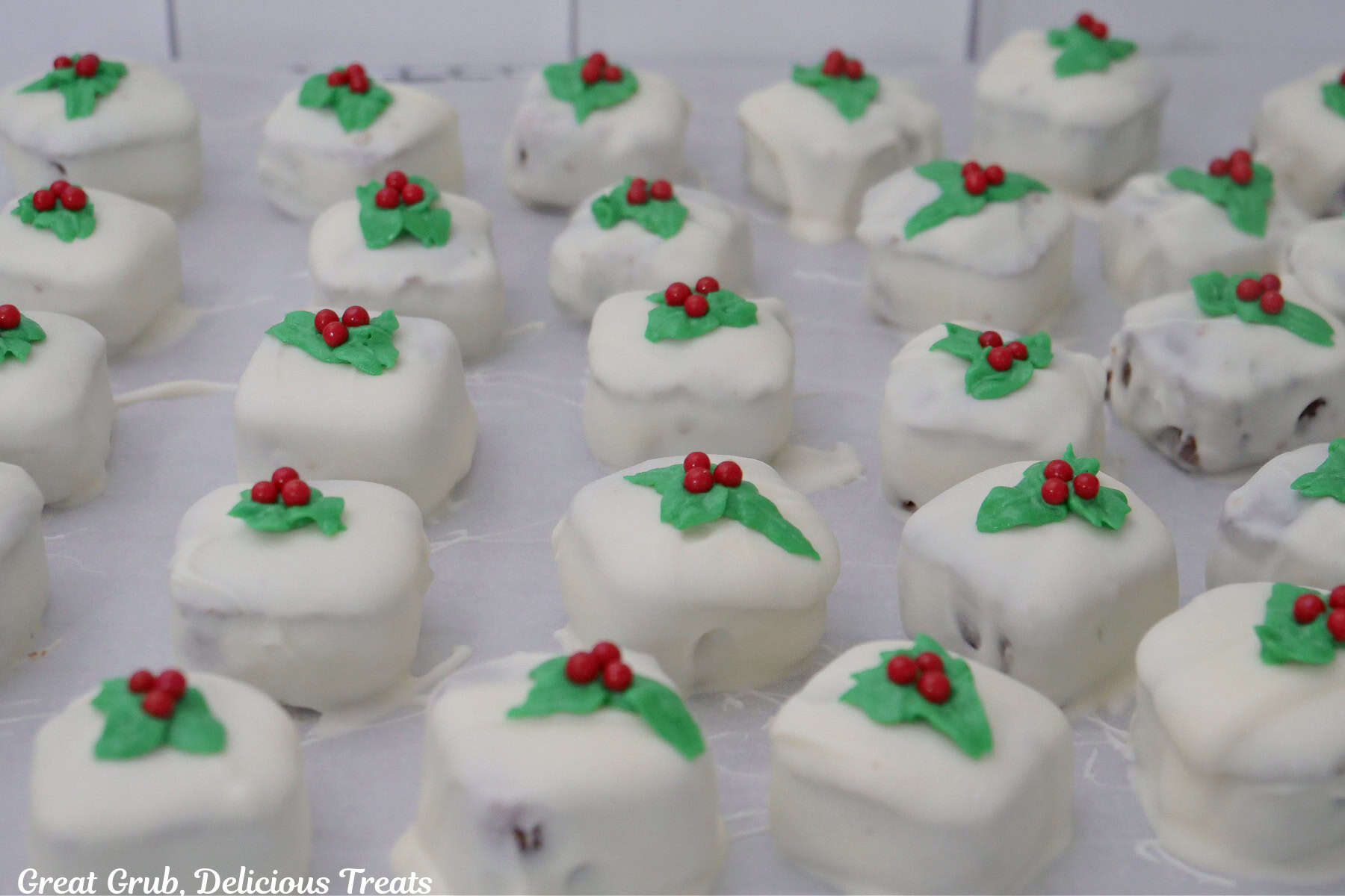A baking sheet covered with parchment paper with white chocolate covered gingerbread bites on it.