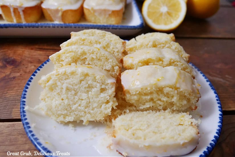 A wood surface with two white plates with blue trim with small lemon loaves on them.