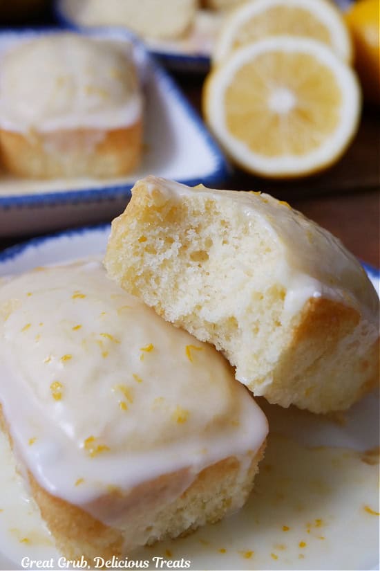 A white plate with blue trim with two mini lemon loaves on it with a bite taken out of one of the loaves.