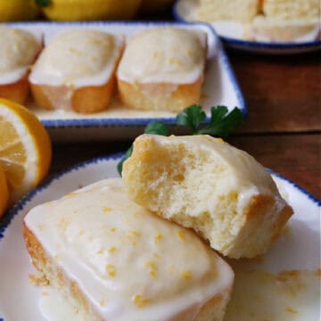 Two lemon mini loaves on a white plate with blue trim.