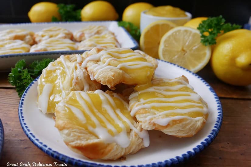 A horizontal photo of a wood surface with two white plates with blue trim with mini lemon pastries on them.
