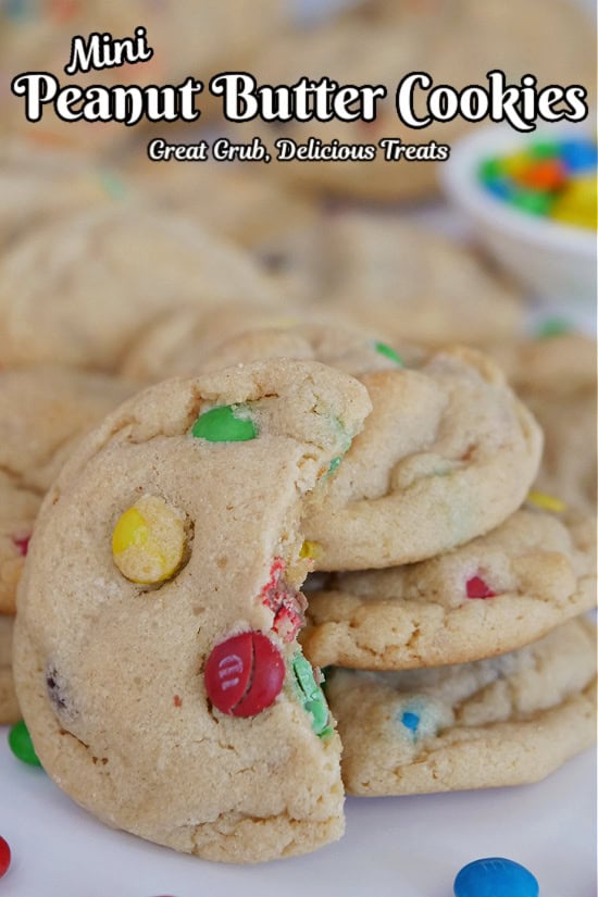 A white surface with mini peanut butter cookies placed all over the surface with a few stacks of cookies and one with a bite taken out of it.