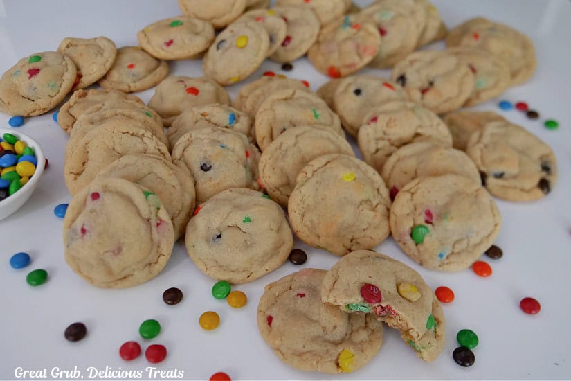 A white surface with 4 dozen mini cookies on it with mini M&Ms scattered around.