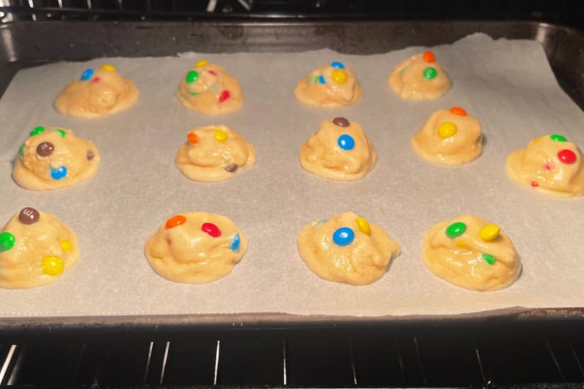 A baking sheet in the oven with mini cookies on it baking.