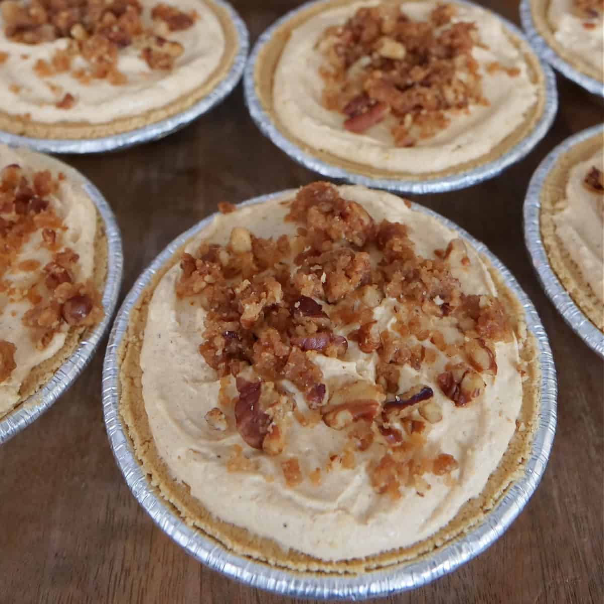 A wood surface with several mini pies on it.