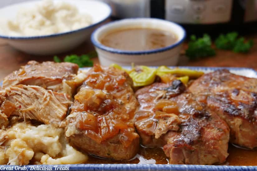 Four slow cooked pork chops on a white plate with blue trim.