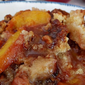 A white bowl with blue trim filled with nectarine cobbler.