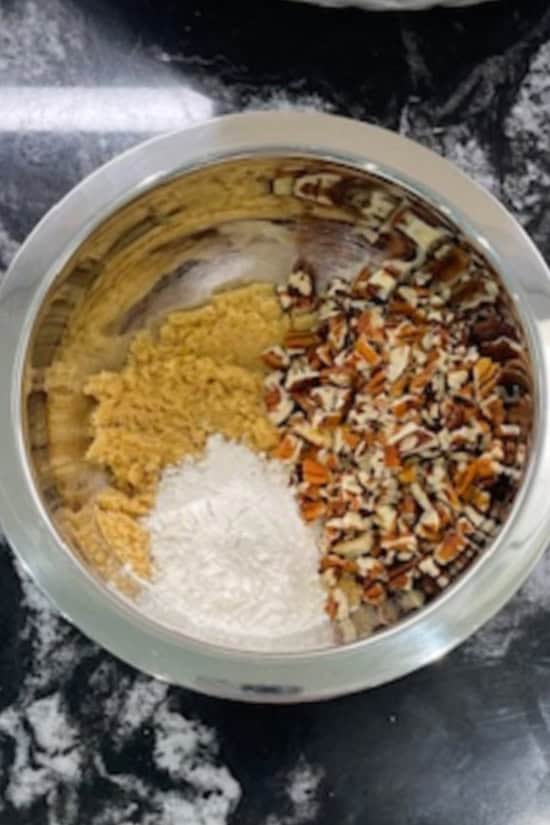 A sliver bowl with the ingredients added to make the brown sugar pecan topping for the cobbler.