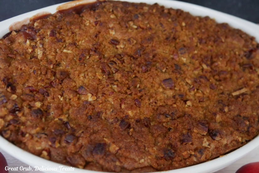 A white ovel baking dish with the baked cobbler right after being removed from the oven.