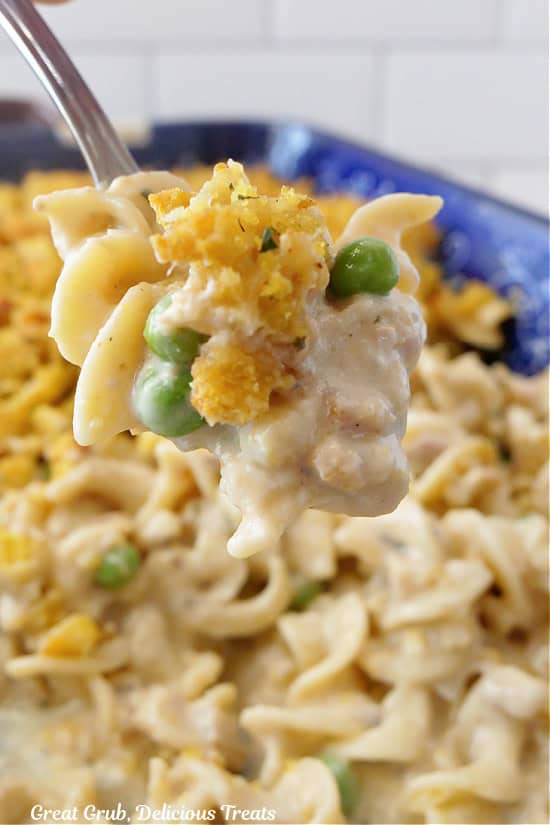 A spoonful of tuna noodle casserole held above the baking dish.